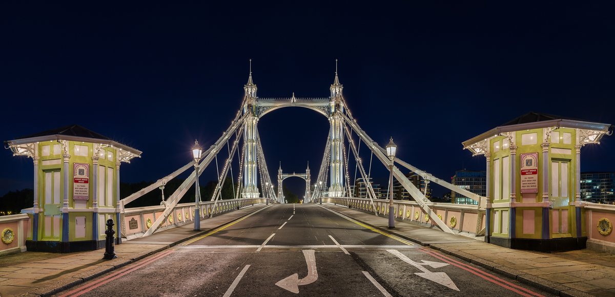 Albert Bridge in Chelsea outlined in lights at night, seen straight down the roadway.