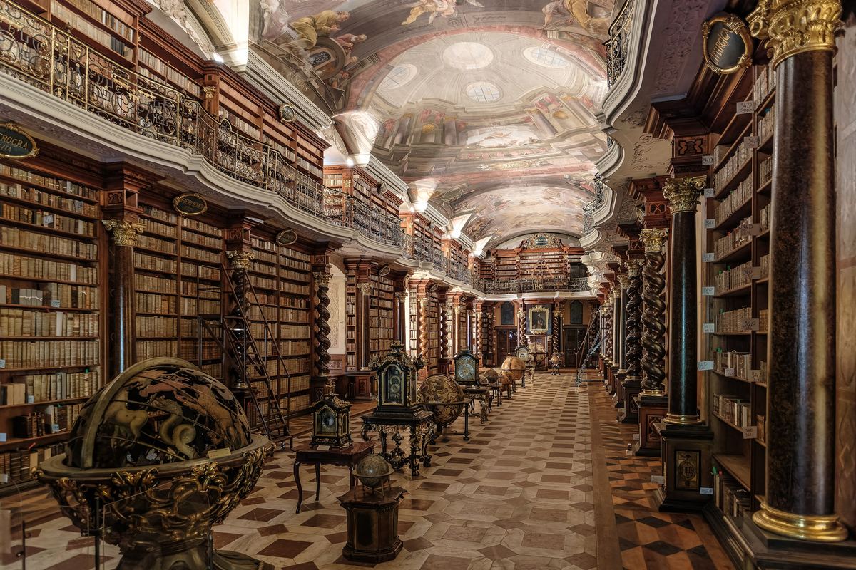The Baroque Library Hall of the Clementinum in Prague: carved bookcases, a painted ceiling and a row of antique globes.