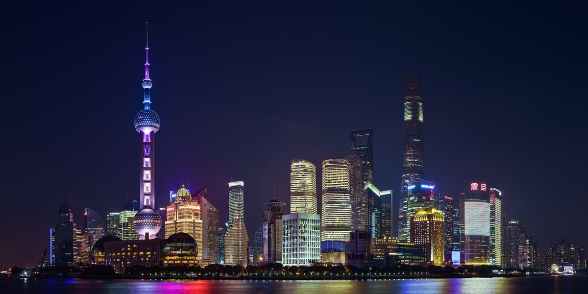 The towers of Pudong lit up at night across the Huangpu River, with the Oriental Pearl Tower on the left.