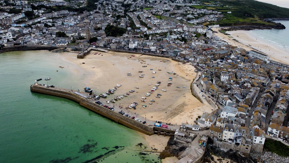 St Ives harbour and town from the air, with the curved pier and sandy harbour beach.