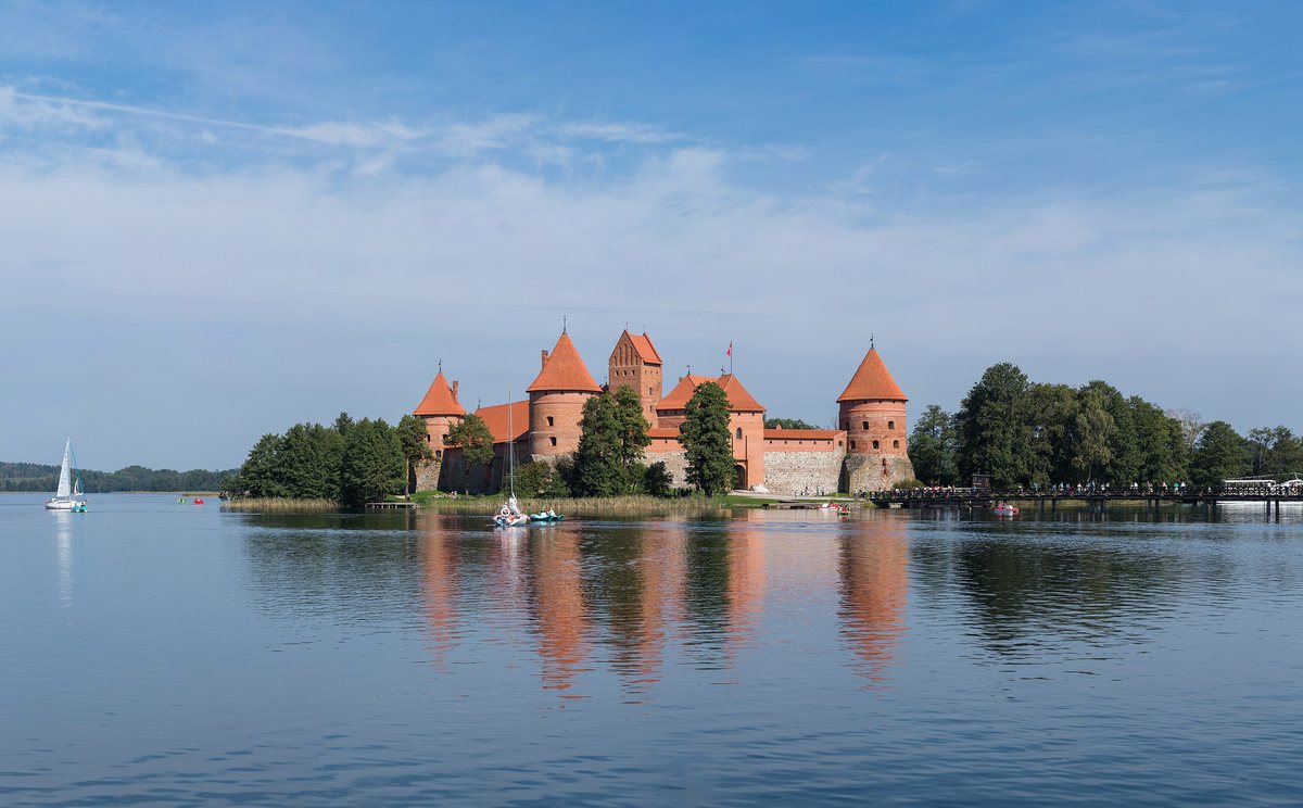 The red-brick Trakai Island Castle on a lake, reflected in calm water.