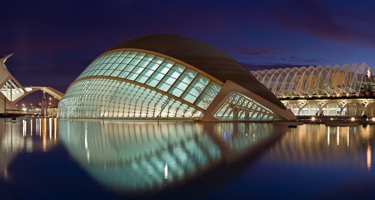 The eye-shaped Hemisferic building in Valencia's City of Arts and Sciences, lit at twilight and mirrored in its pool.